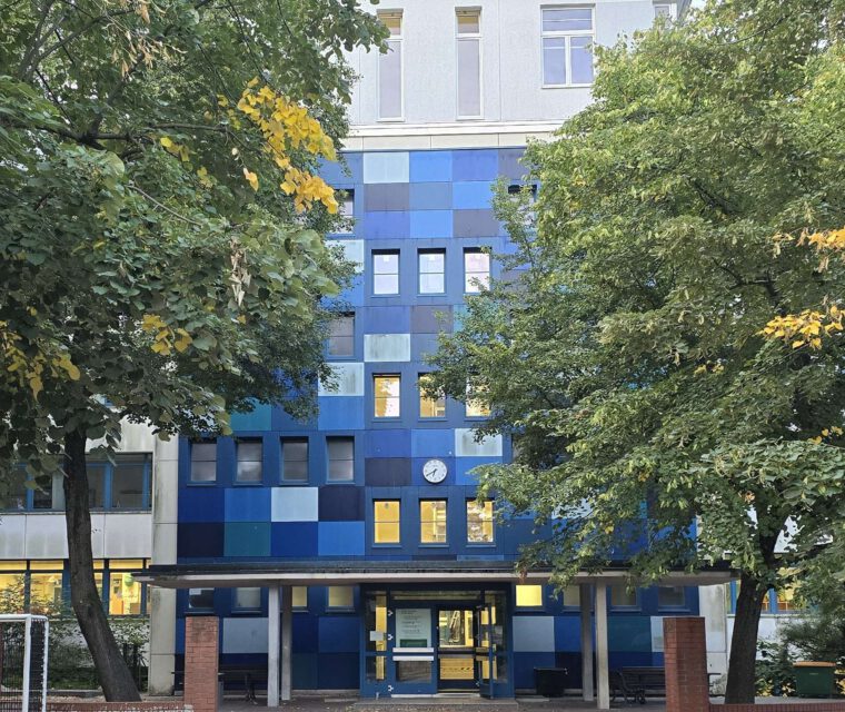 Neue Außenuhr an der blauen Schulfassade über dem Eingang der Modersohn-Grundschule